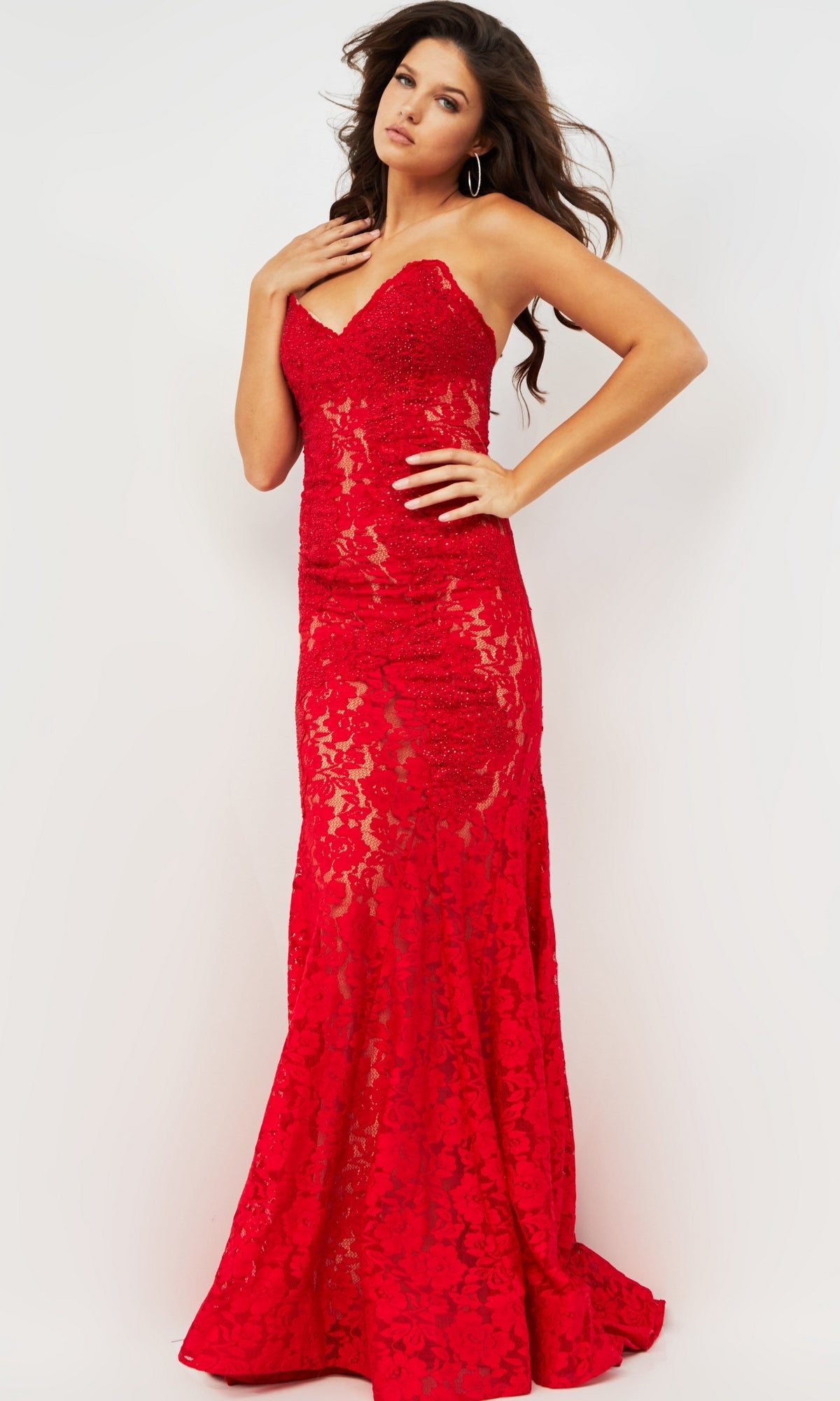 A woman poses in the Long Prom Dress 37334 by Jovani—a strapless, floor-length red lace gown with a sweetheart neckline, fitted bodice, and flared hem—against a plain white background.